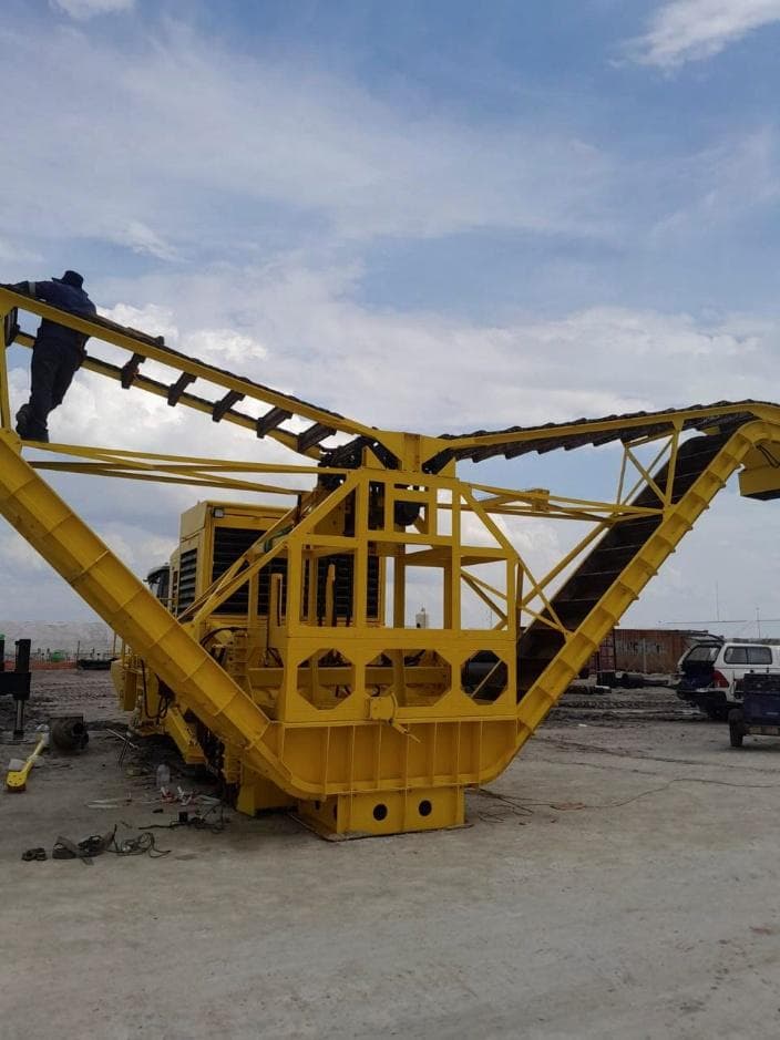 Yellow salt harvester with an angled conveyor frame on the salt pan